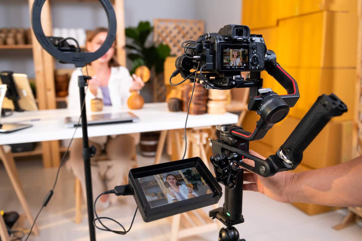 Woman presenting product in front of camera and product video production crew