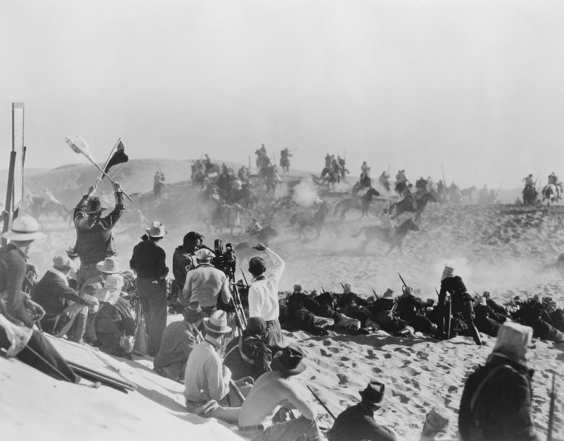 Early film crew capturing wild west film in desert