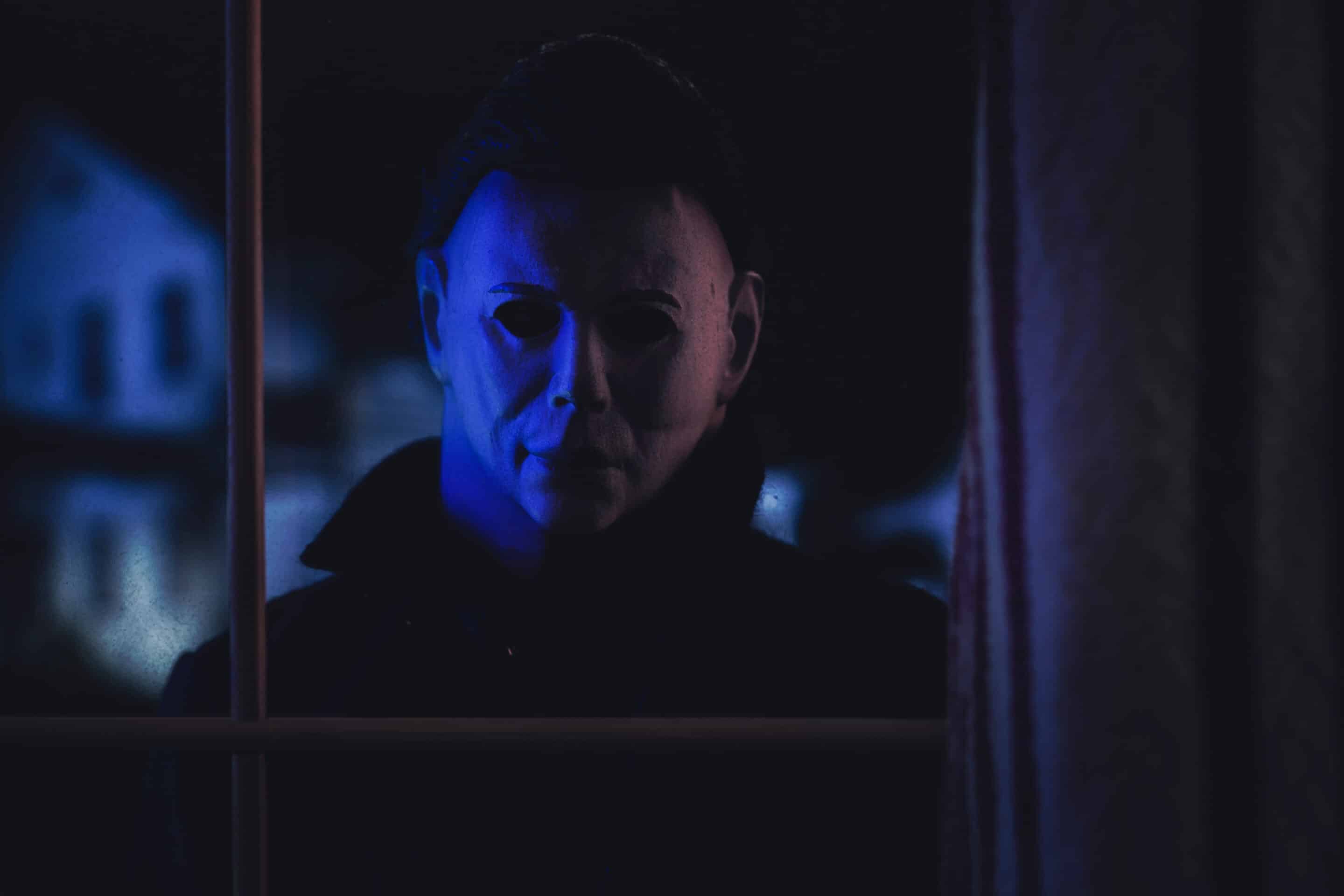 NEW YORK USA: APRIL 14 2021: Halloween horror movie slasher Michael Myers staring through a window at the Doyle house - Trick or Treat Studios action figure Michael Myers horror film character peering through Utah window