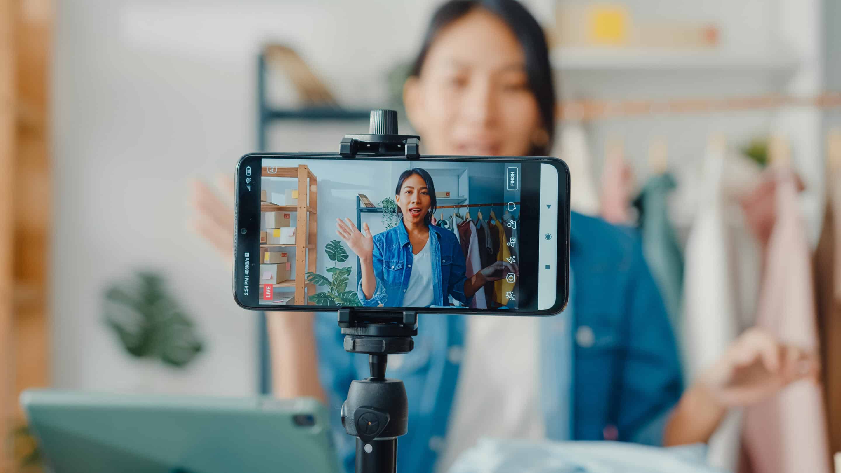 A person filming a video for social media using a smartphone mounted on a tripod.