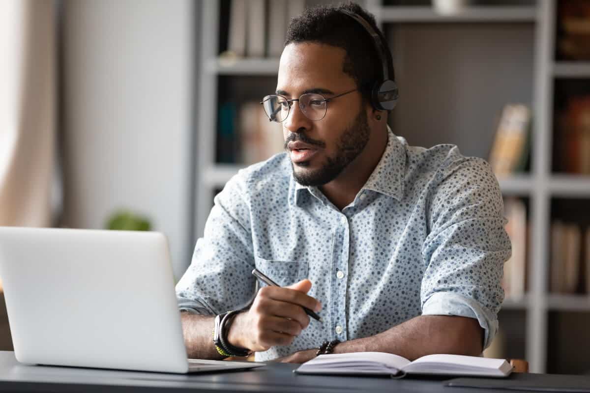 Employee watching training video on his laptop while taking notes