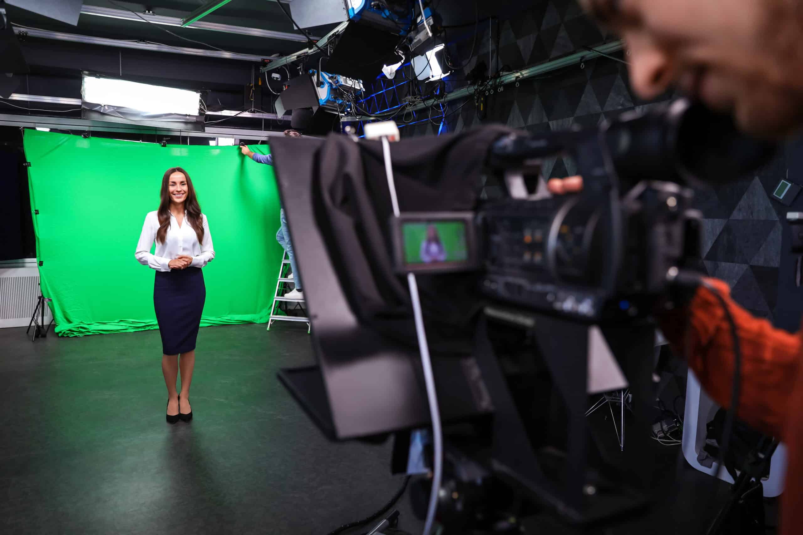 Cameraman pointing camera at businesswoman in front of a green screen