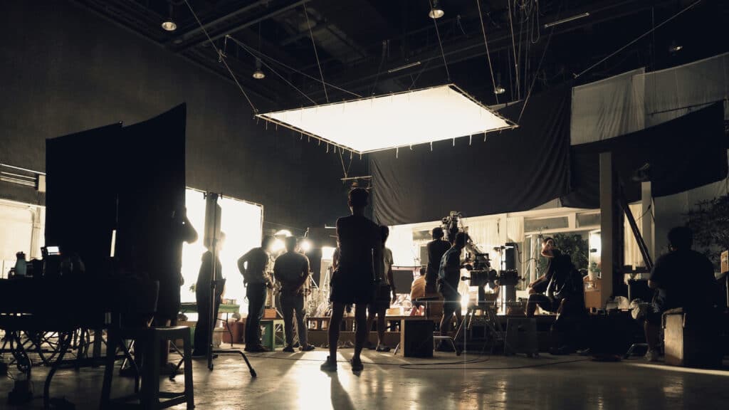 Behind the scenes of people working in a full-service video production studio making a movie, film, or video commercial.