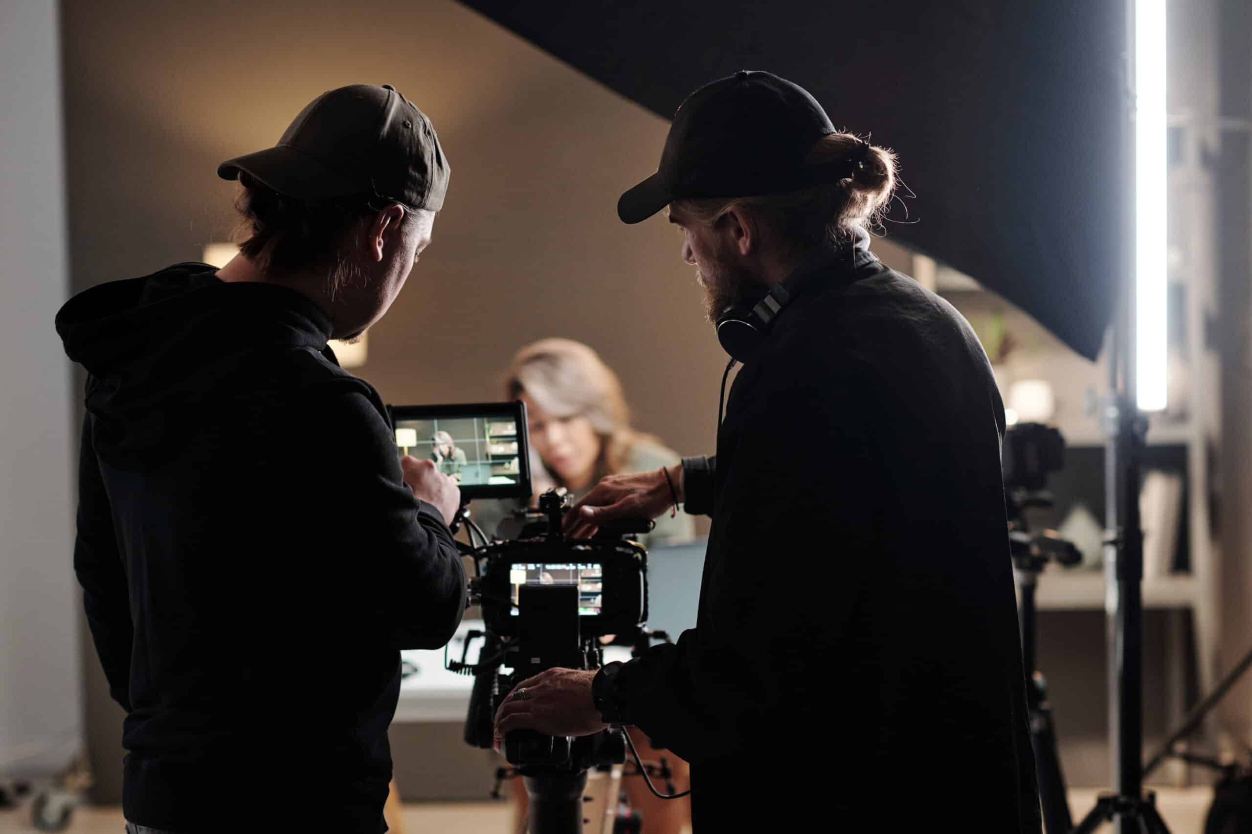 Back view of two men standing in front of a camera while shooting a new commercial for a client.